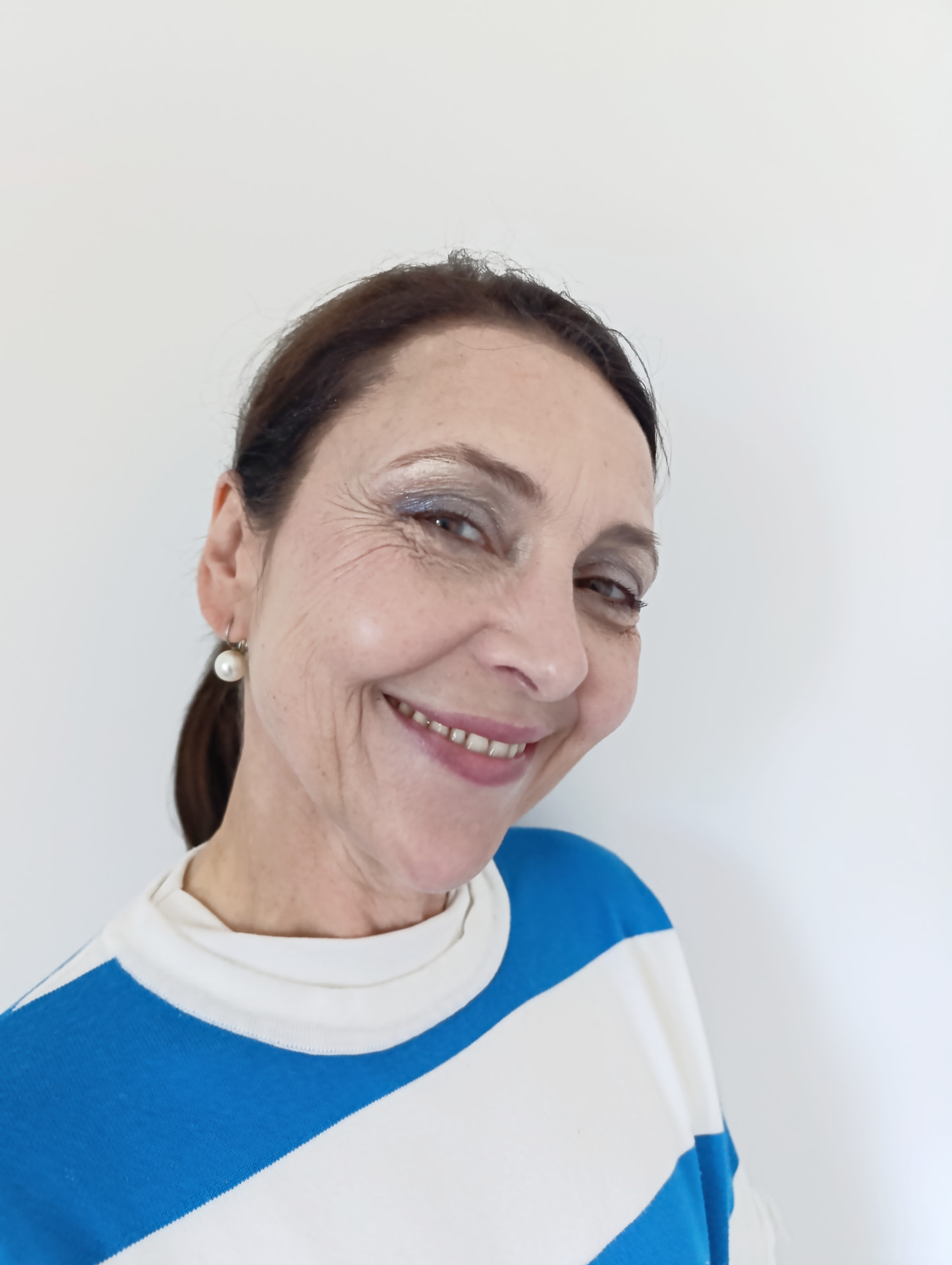 Kundin mit silbrig schimmerndem Lidschatten, dezentem Lippenstift und Perlenohrring