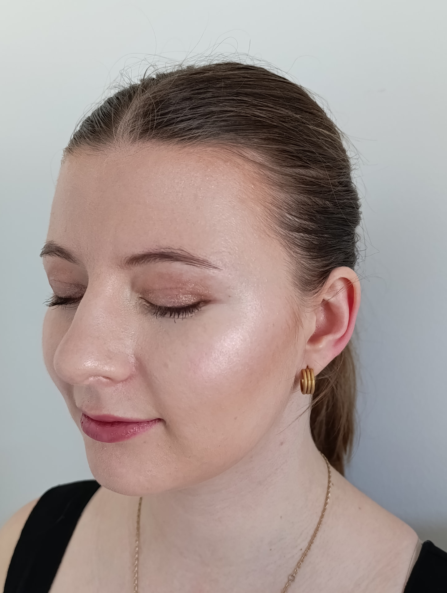 Kundin mit strahlendem Highlighter, zartem Glitzer-Lidschatten und sanfter Lippenfarbe